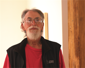 A headshot of a man in a vest