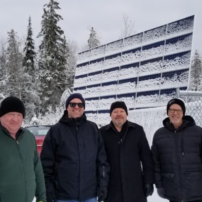 A group in front of a snowy solar panel