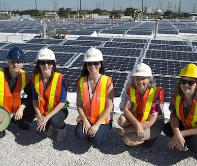 A group of people sitting in front of a roof of solar panels