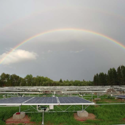 A field of solar panels with a rainbow in the sky over them